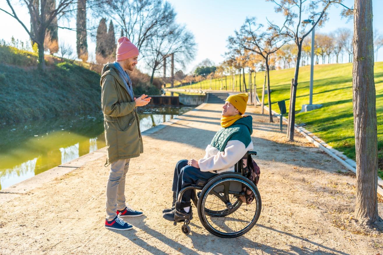 man-talking-to-friend-sitting-in-wheelchair-in-par-2025-01-16-02-34-27-utc